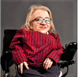 Kuvassa Anni Kyröläinen istuu pyörätuolissa ja hymyilee.