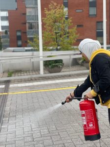 Nainen harjoittelee palosammuttimen käyttöä.