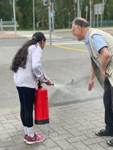 Naiselle opastetaan palosammuttimen käyttöä.